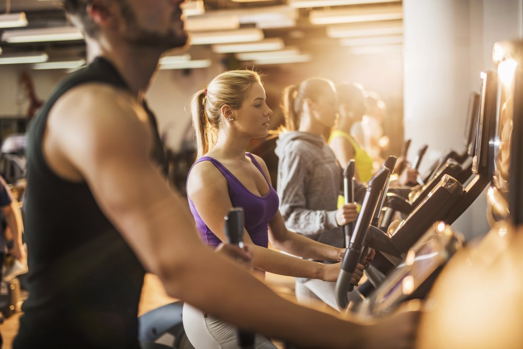 Group of people exercising on exercise machine in a gym. Group of people exercising on exercise machine in a gym.